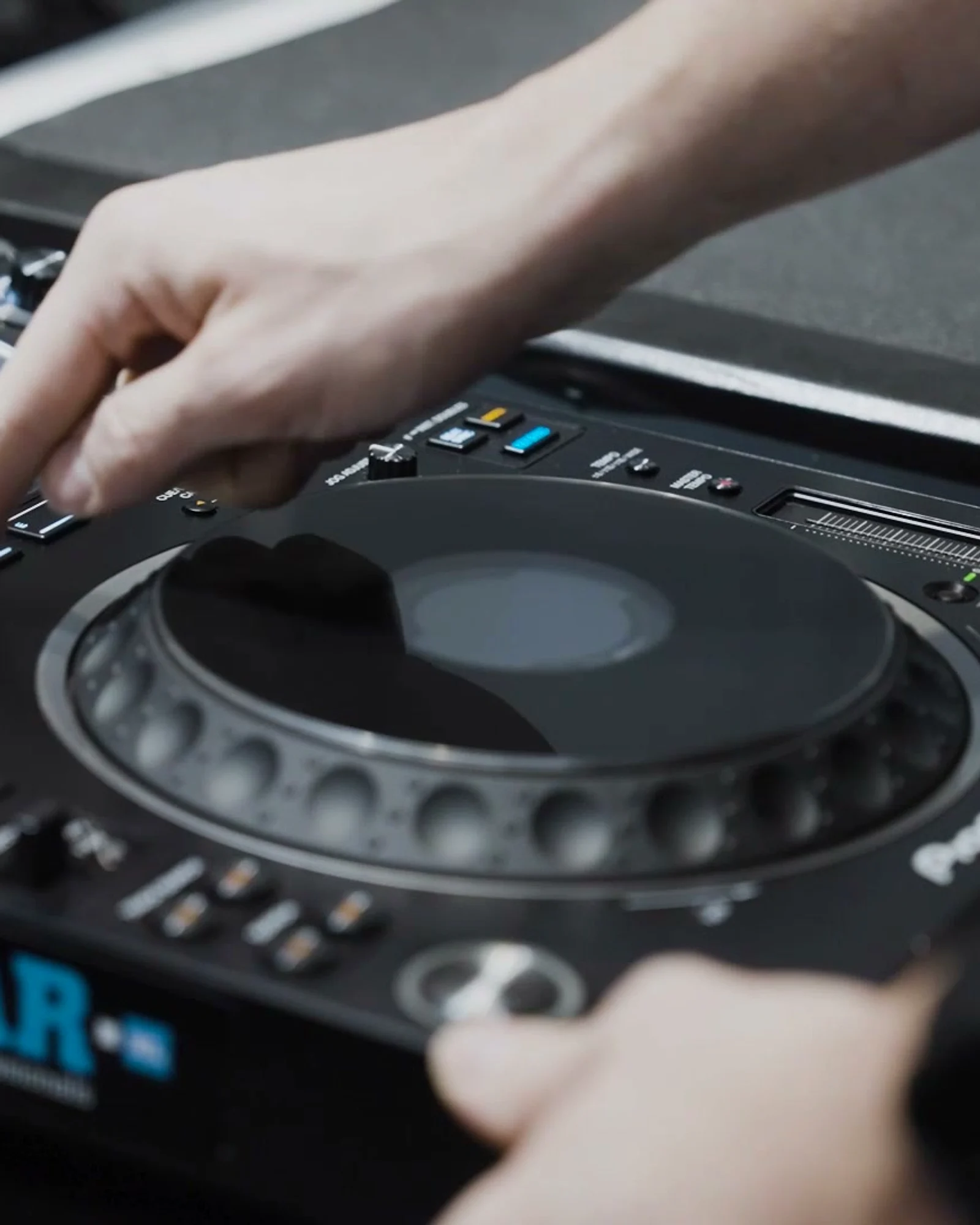 Hands working a DJayGear-branded CDJ — finger on cue, jog wheel in frame